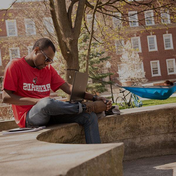Student sitting on a concrete bench on the quad.